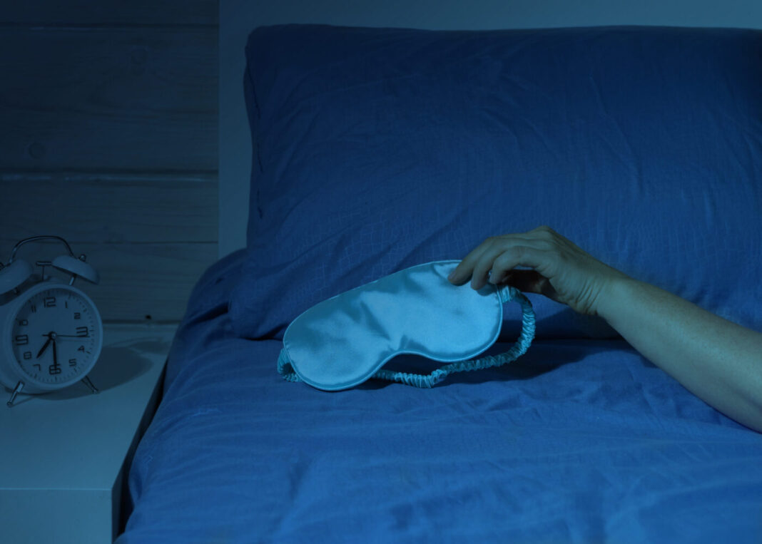 A woman's hand takes a sleep mask. Optimization of the circadian rhythm. Fight insomnia.