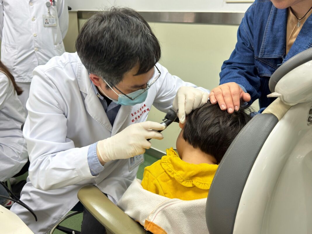 Dr. Yilai Shu examines a young patient at the Eye & ENT Hospital of Fudan University [
