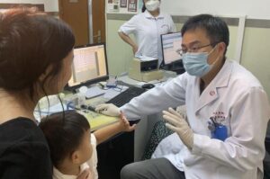 Dr. Yilai Shu communicates with a young patient at the Eye & ENT Hospital of Fudan University in Shanghai, China.